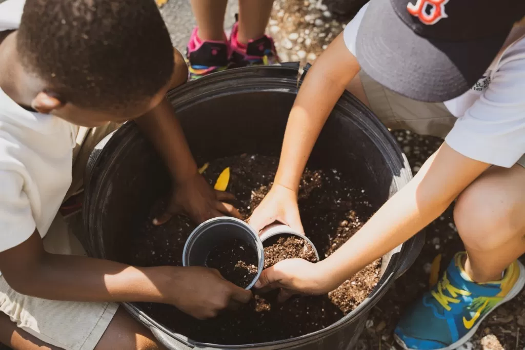 Person's hands mixing potting soil on a gray tarp