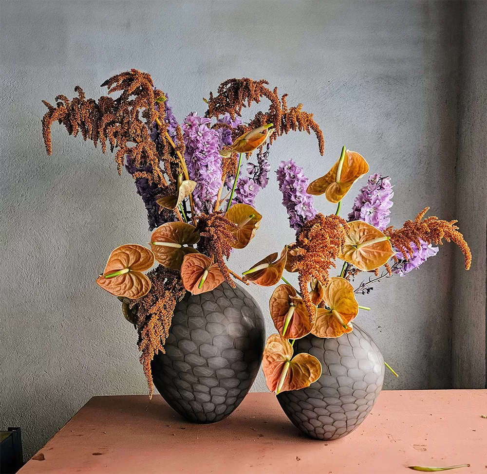 Sculptural floral arrangement featuring dried grasses and Gladiolus in a modern Brutalist style vase, highlighting 2025 floral trends.
