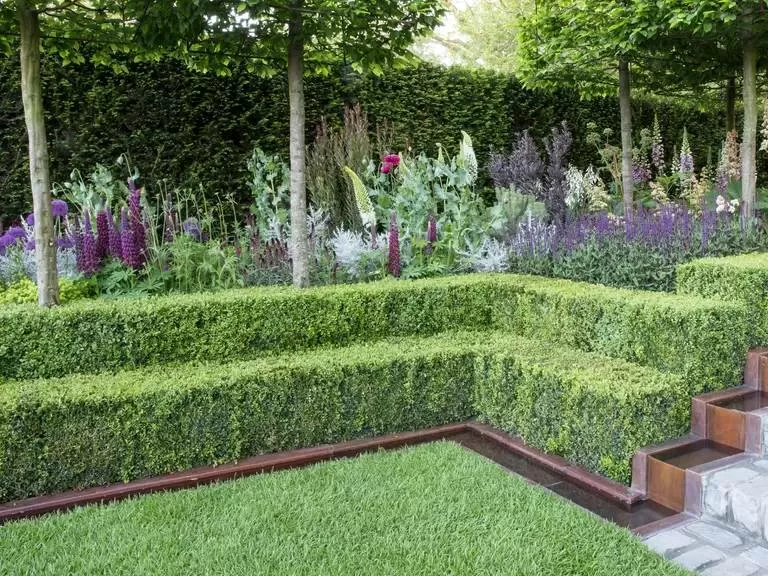 Corten steel landscape edging curves around a garden bed next to a lawn