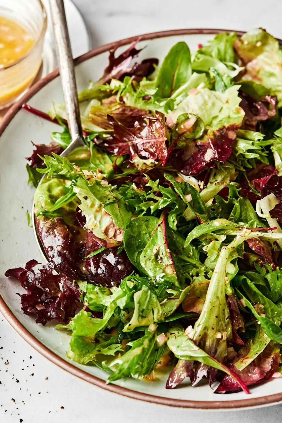 Fresh mixed leafy salad greens tossed with vinaigrette in a bowl